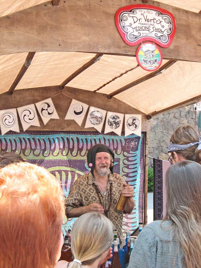 A photo of a man dressed as an old fashioned joker selling mind medicine