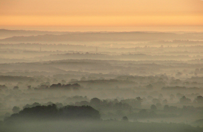 A beautiful salmon/pink sunrise over misty green valleys.