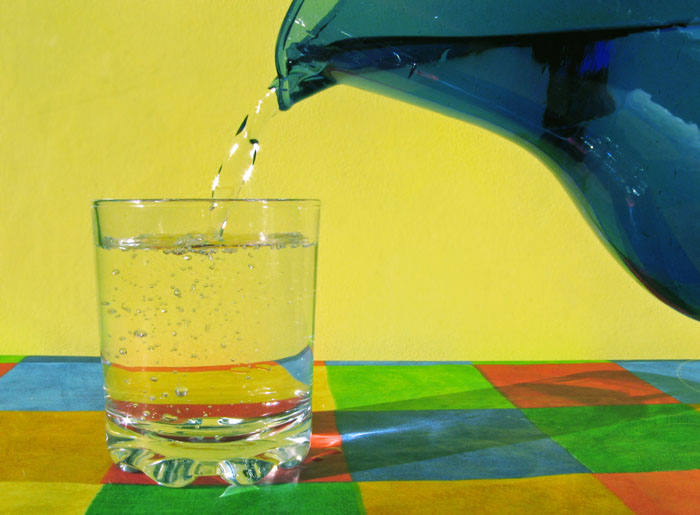 A blue glass jug pours water into a glass.