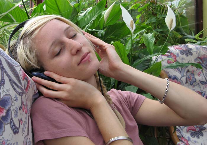 A young woman led back on a sofa listening to music via headphones